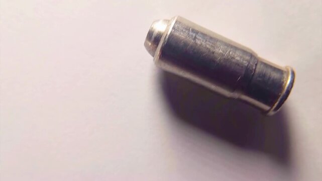 Close-up view of a small, silver-colored metallic cylindrical object on a white background.