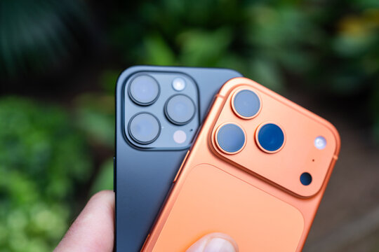 Tarragona, Spain - October 26, 2025: Close-up of a man holding an orange iPhone 16 Pro and 17 Pro in his hand.