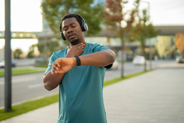African american man checking pulse and fitness tracker