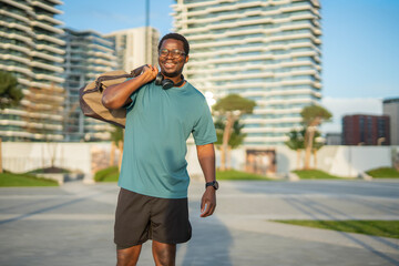 Smiling black man walking carrying duffel bag urban area