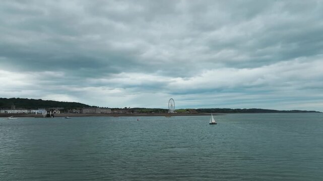 Beaumaris⁩, Wales, fast orbit on Manai Strait with sailing boats, town and ferris wheel in the background