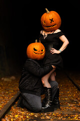 Creative couple in Halloween costumes with pumpkin heads enjoying a fun moment in a spooky autumn setting