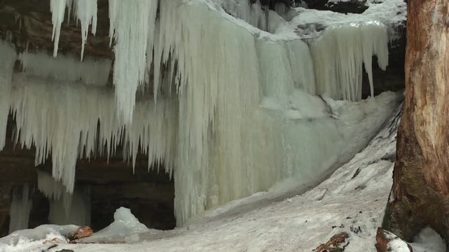 Thick icicles and ice sheets hang from rocky overhang at Eben Ice Caves, USA.