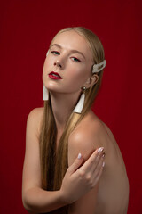 Fashion photo of a blonde girl with long hair on a red background