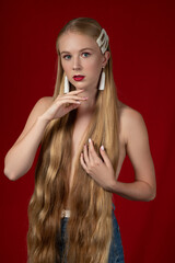 Fashion photo of a blonde girl with long hair on a red background