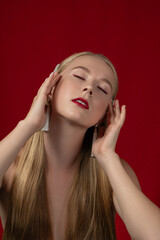 Fashion photo of a blonde girl with long hair on a red background