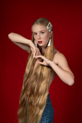Fashion photo of a blonde girl with long hair on a red background