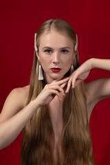 Fashion photo of a blonde girl with long hair on a red background