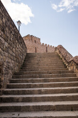 Ancient stone steps lead to historic castle battlements against a blue sky in a quiet, scenic location