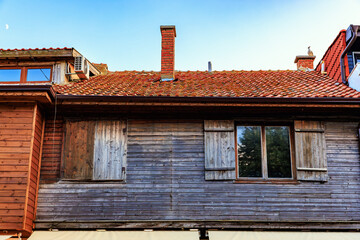 Rustic cottage with wooden shutters and tiled roof under clear sky