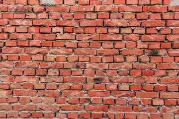 Red brick wall with weathered surface in urban setting