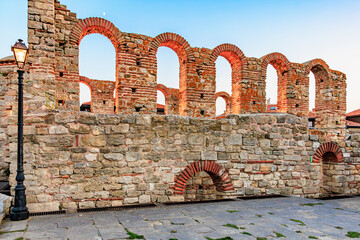 Ancient stone walls with arched openings at sunset in historical ruins