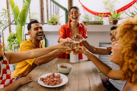 Young Brazilian adults cheering with beer at barbecue table