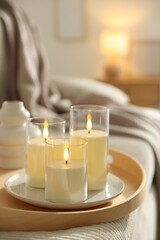 Beautiful LED candles on sofa indoors, closeup. Space for text