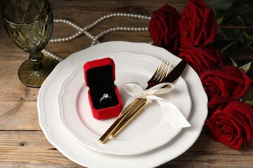 Romantic place setting. Box with engagement ring, plates, cutlery, napkin, rose flowers and glass...
