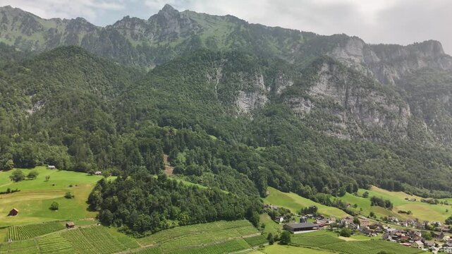 Aerial Drone View of the Swiss Alpine Valley with Green Fields, Rolling Hills, and Majestic Mountains near Flums, Berschis, and Walenstadt in the Canton of St. Gallen, Switzerland