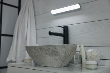 Portable LED light on wall over sink in bathroom