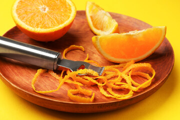 Orange zest, fresh fruit and zester tool on color background, closeup