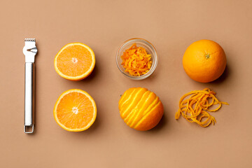 Orange zest, fresh fruits and zester tool on beige background, flat lay