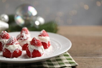 Christmas food. Santa hats made of strawberries, whipped cream and decor on wooden table against background with blurred lights, space for text. Bokeh effect