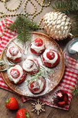 Christmas food. Santa hats made of strawberries, whipped cream, rosemary and decor on wooden table, flat lay