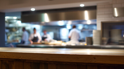 Open plan kitchen with blurred chefs preparing food, warm lighting, wooden counter in foreground, modern restaurant interior, professional atmosphere, busy and inviting