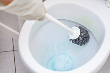 A man washes a toilet. He cleans the toilet to maintain cleanliness and hygiene