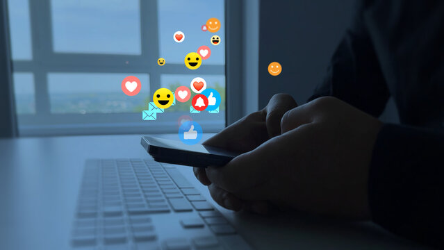 Person using smart phone with emoticon icons of Social Media.Interactive with friends on chat with emoticon feedback.Social media,marketing, like,social network,blog,live,chat reaction and livestream. - Powered by Adobe