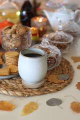 Lit candles, cookies, chocolate, nuts, tea, wine, pumpkins, books, reading glasses and autumn leaves on the table. Autumnal hygge at home. Selective focus.