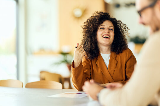 Fototapeta Happy Woman in Brown Blazer Laughing During Casual Business Meeting With Colleagues
