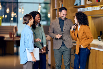 Group Of Four Colleagues Having A Friendly Business Conversation In A Modern Cafe Office
