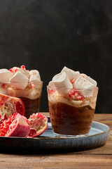 Hot chocolate with marshmallows and pomegranate in a glass on a blue plate