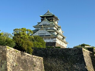 Fototapeta premium Historic Japanese castle with stone walls under blue sky