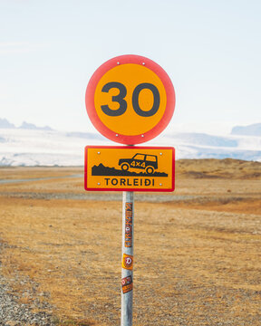 View of a road sign with a speed limit and a 4x4 vehicle warning in a landscape with distant glaciers, Jokuls&aacute;rl&oacute;n, Sveitarf&eacute;lagio Hornafjorour, Iceland.