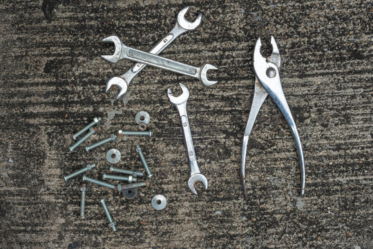 Used socket wrenchs and slip joint plier for a repair task laid on concrete texture