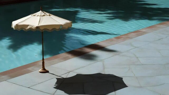 Beige patio umbrella by a blue pool casts a shadow on the sunlit pool deck.