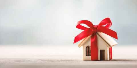 Home wrapped with red bow symbolizes real estate gifts for new homeowners and celebrations