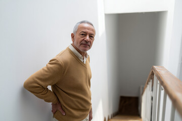 Older man suffering from back pain on the stairs
