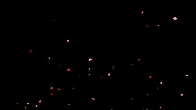 A romantic explosion of red confetti flutters down against an isolated black background. For Valentine's Day, weddings, or celebrations