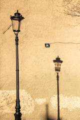 A lamppost with a shadow against a wall.