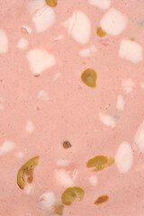 A close-up shot captures the pink, smooth texture of a mortadella slice, studded with white fat chunks and green olive pieces