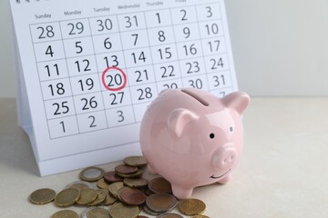 Saving money. Piggy bank, coins and calendar on light table