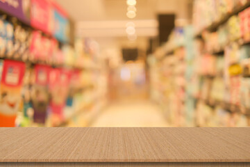 blur local supermarket convenience store background with beige wood perspective tabletop to showing product or ads banner and promote marketing on display concept