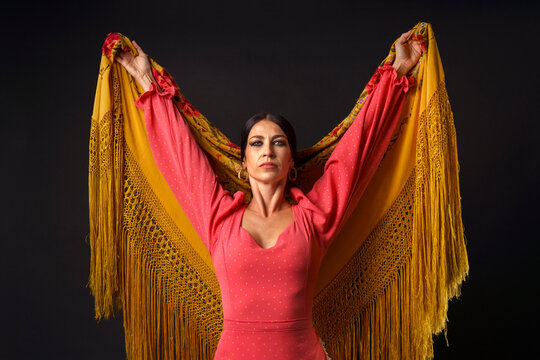Flamenco dancer presenting a colorful manton de Manila shawl with intensity and passion on a dark background