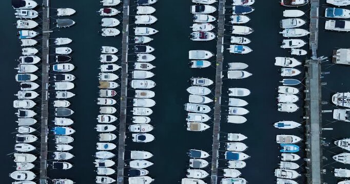 Aerial view of numerous white boats docked neatly in a marina, creating a textured pattern against the dark water, Trieste, Friuli-Venezia Giulia, Italy.