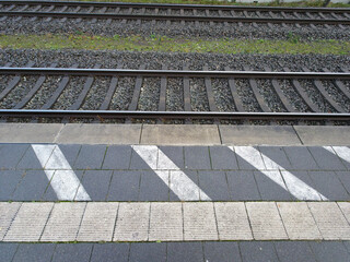 Train tracks with surrounding concrete slabs, ballast bed, and markings in a train station, platform in 27798 Hude, Lower Saxony, Germany