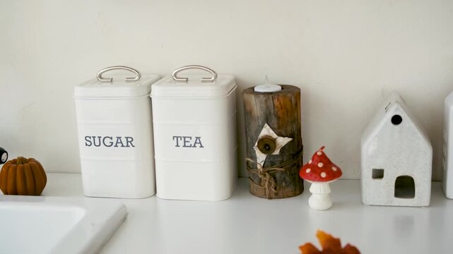 White kitchen canisters labeled SUGAR and TEA with rustic decor and autumn accents