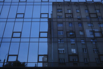 Obraz premium Building reflects on office tower windows, cloudy day.