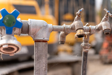 Faucets on a construction site with spider web. Blurry in the background yellow construction site machinery. Selective focus.