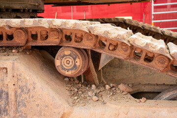 Close up on chain drive of a chain driven excavator, covered with dirt and traces of heavy working.
